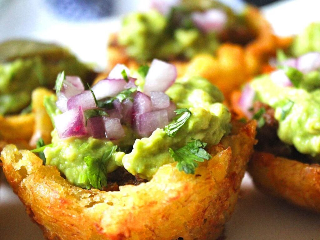 a cup of beautiful stuffed tostones. A baskeck made of platain stuffed with ground beef, guacamole and pickled onions
