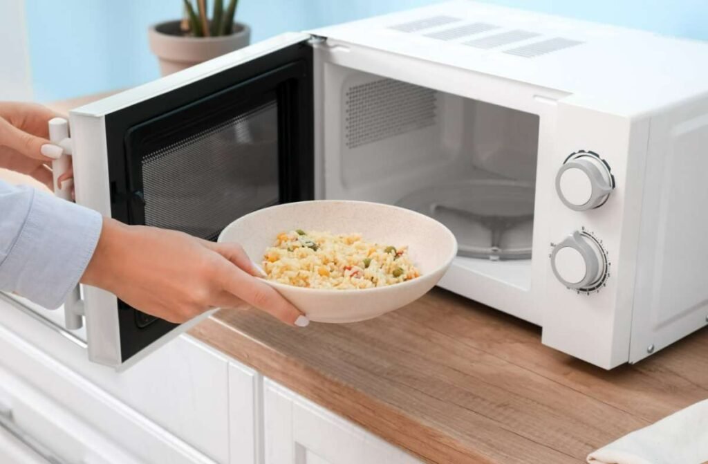 A woman placing a paper bowl in the microwave
